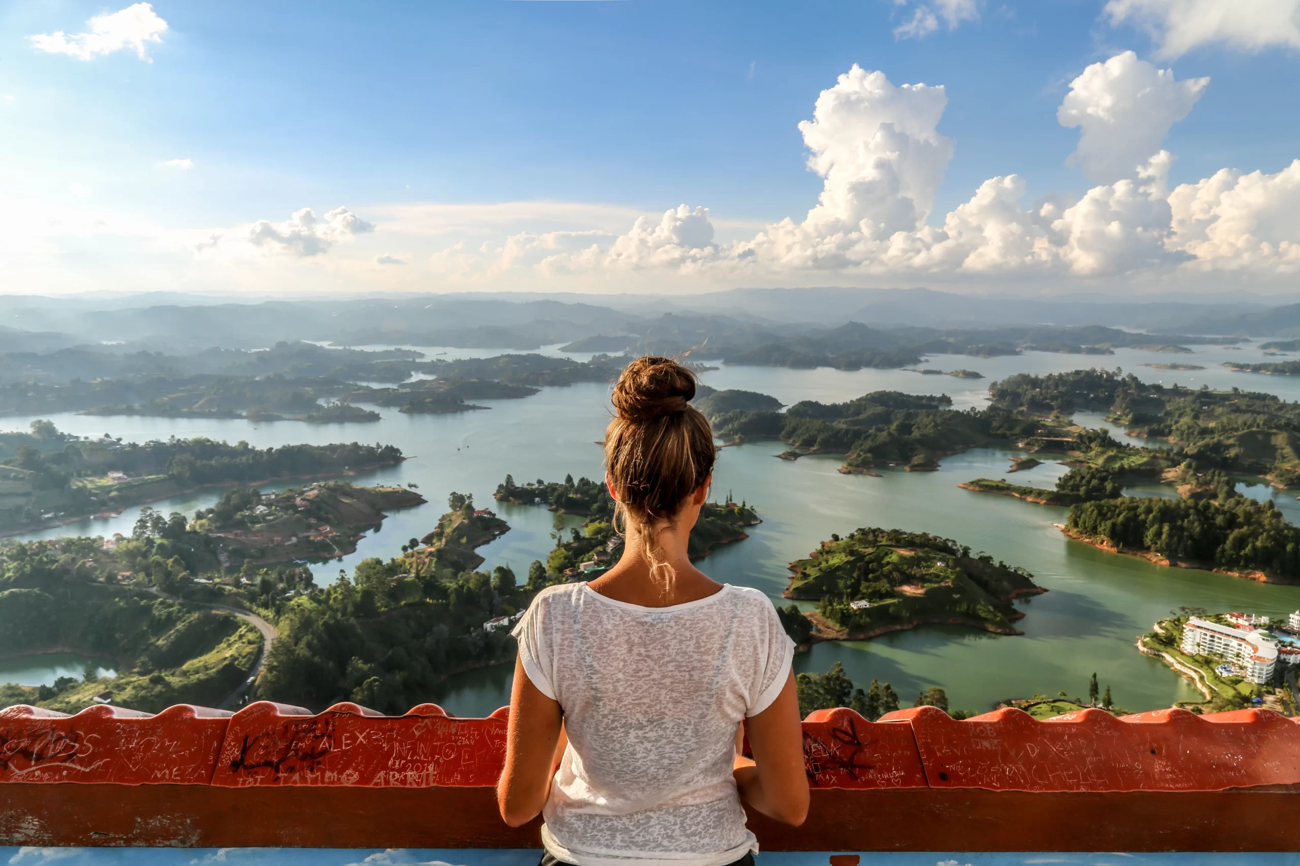 Traveler overlooking the lakes and green islands of Guatapé from a scenic viewpoint in Colombia.