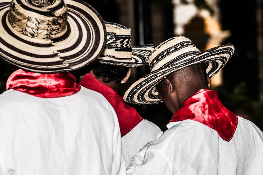 Colombian men wearing traditional sombrero vueltiao hats and red scarves during a cultural celebration.
